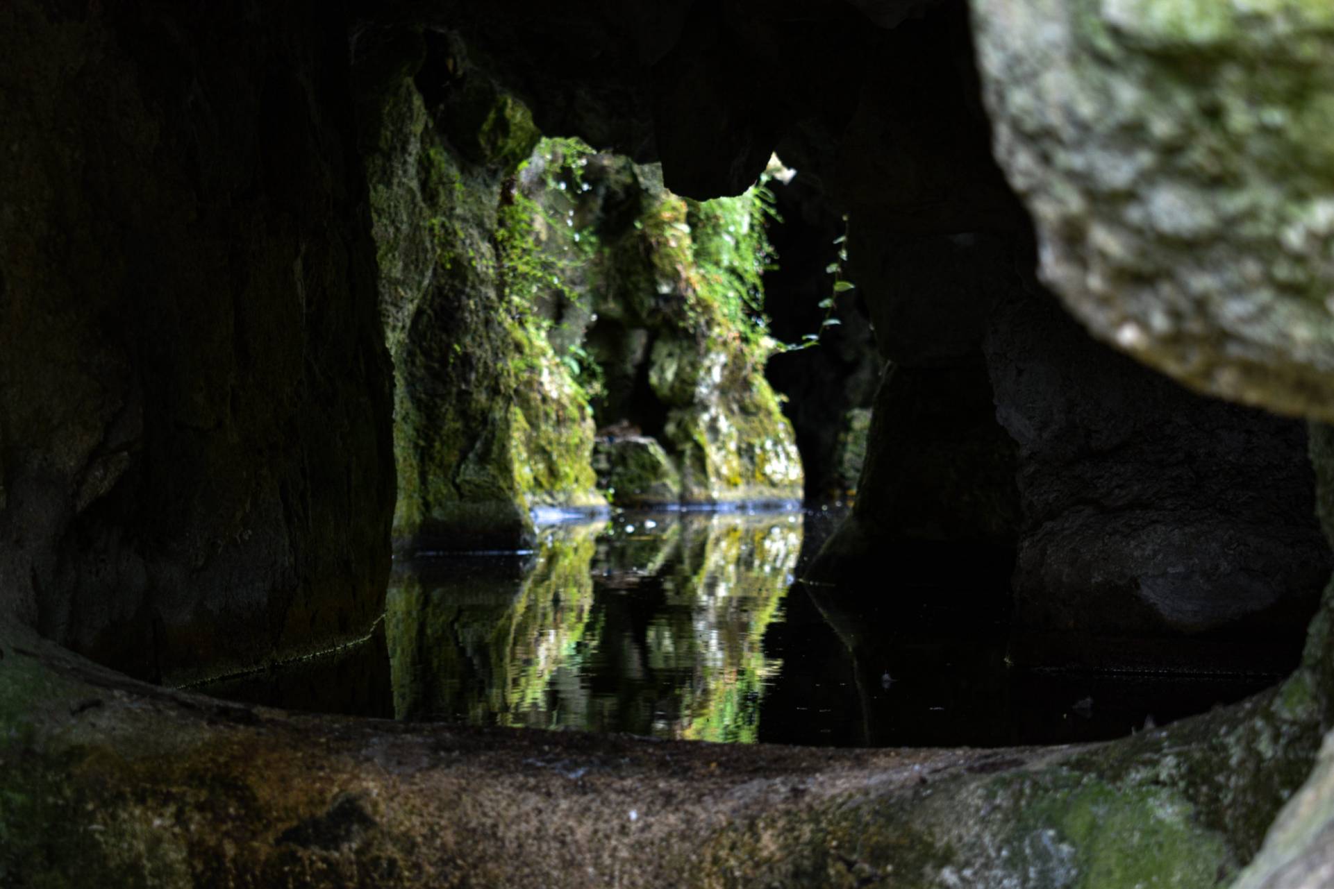 Picture of cave in Sintra castle gardens with water reflecting mossy rock 