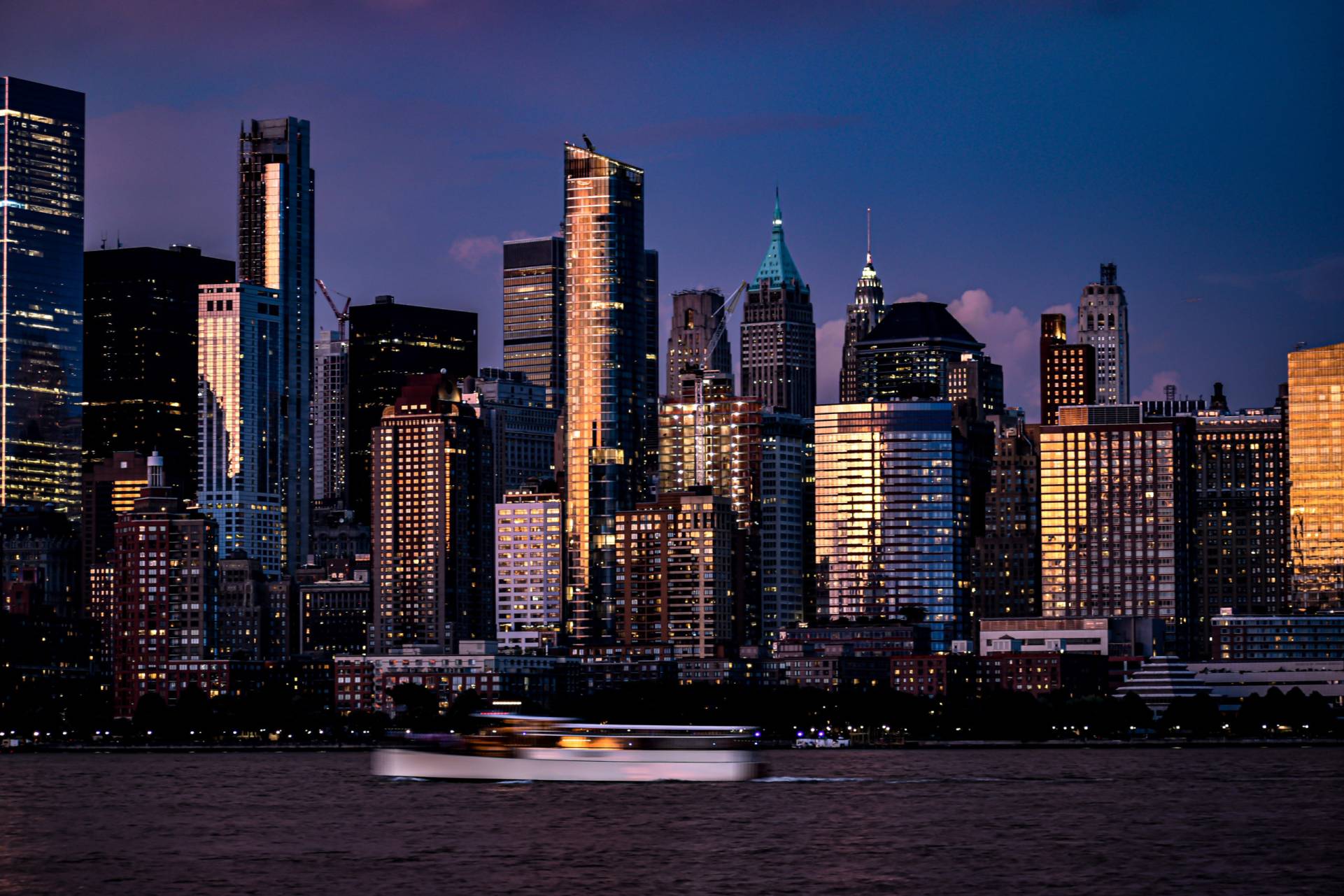 Sunset shot of Hudson Yards from across the Hudson with boat moving in lower frame